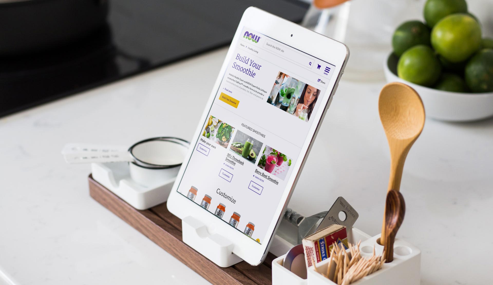 tablet sitting on a countertop showing the Now Foods Smoothie builder web page. tablet is sitting in front of a bowl of limes