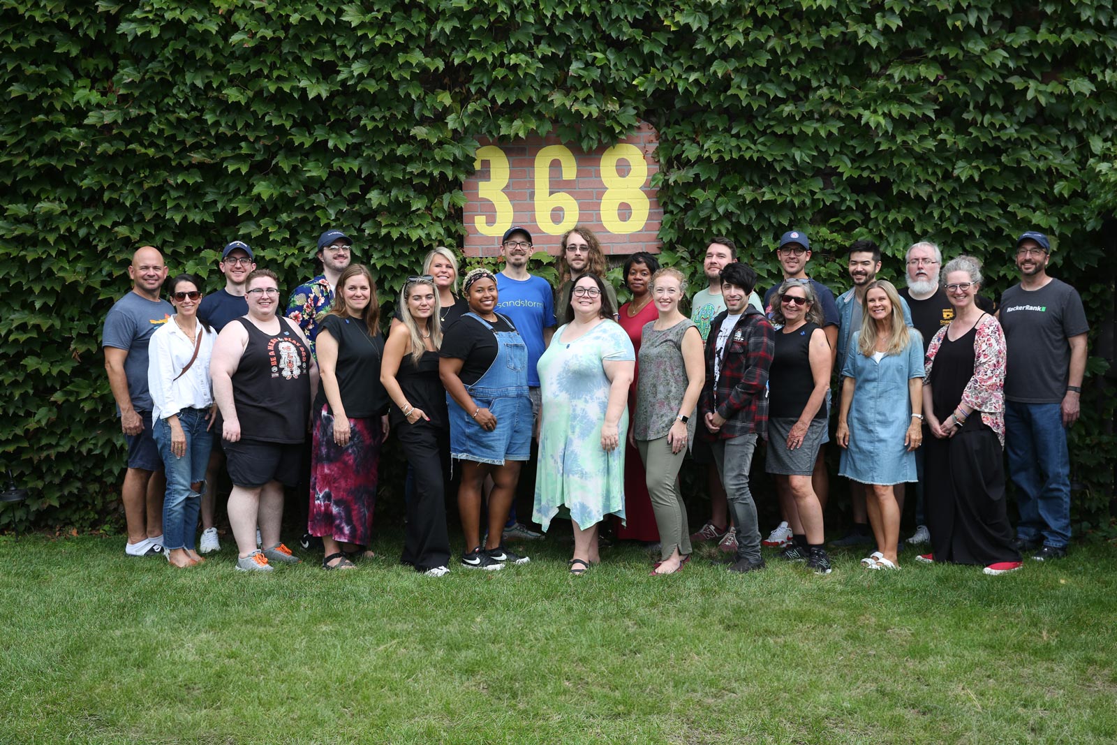 The Sandstorm team stands in front of an ivy-covered wall for a group photo.