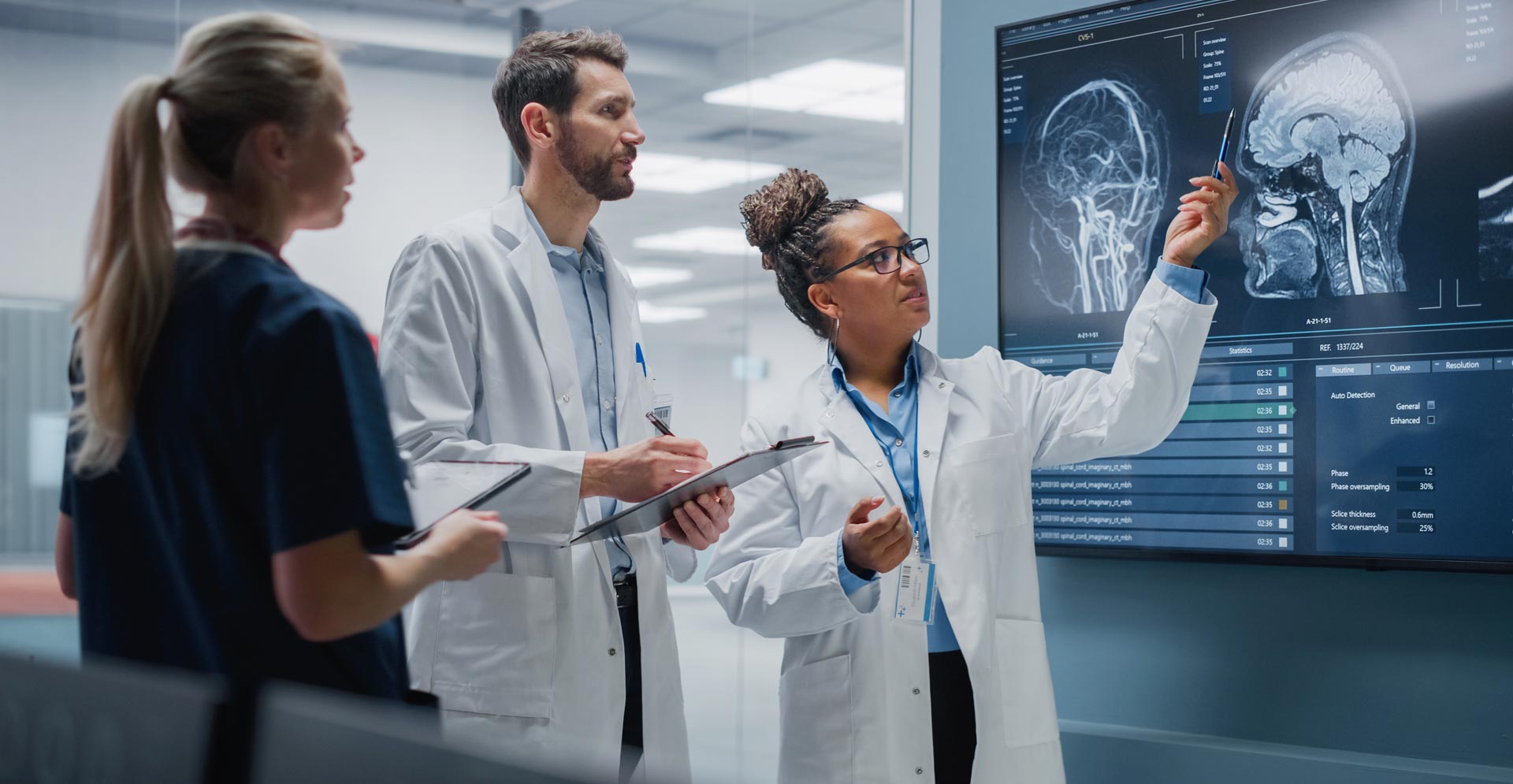 Three medical professionals looking at an MRI of a brain