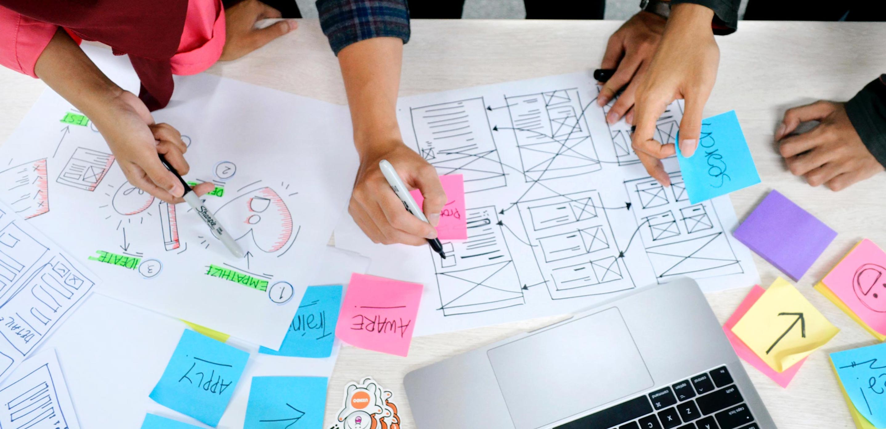 Group of people sketching plans with post it notes and wireframes
