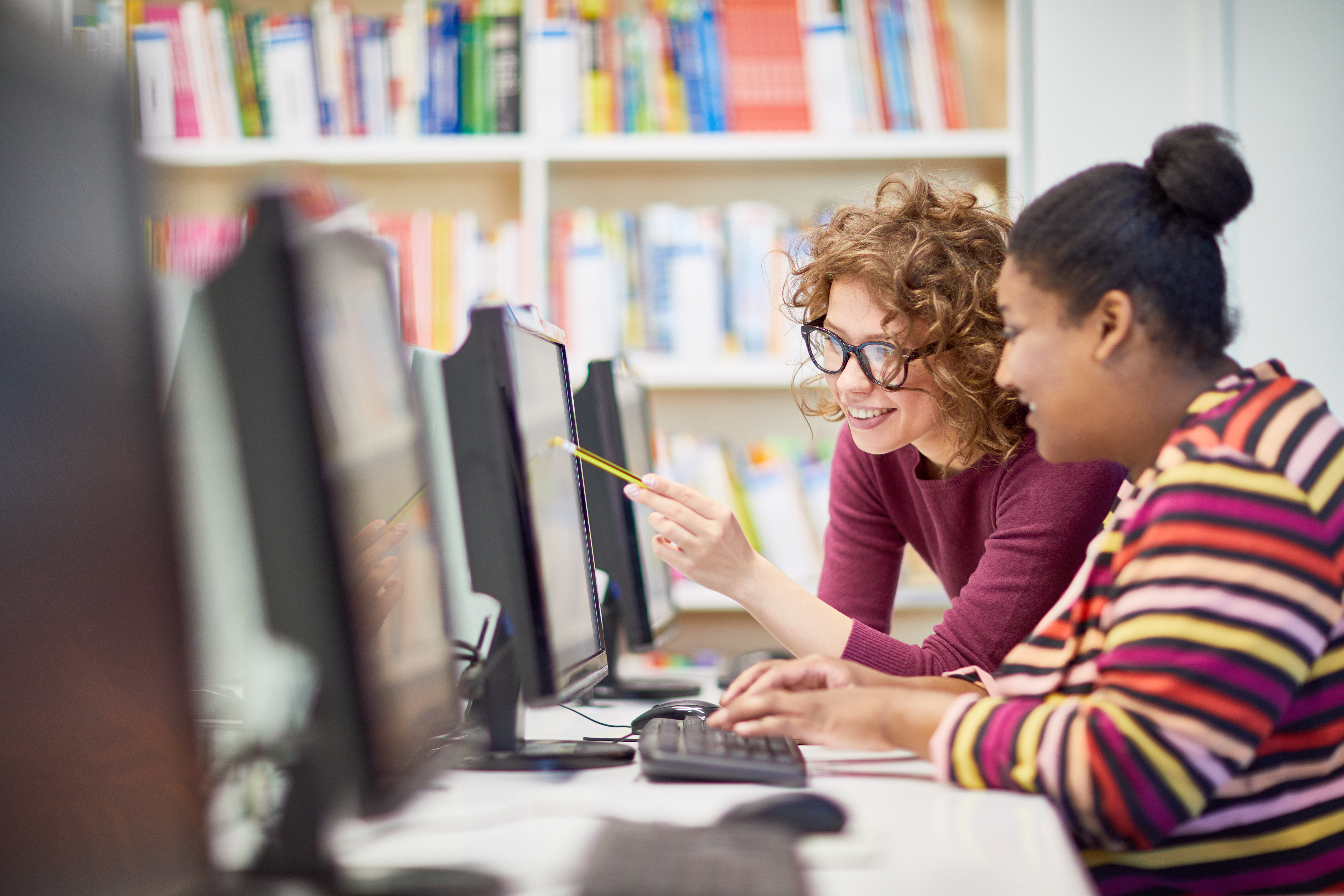 Two female presenting people working together in front of a computer