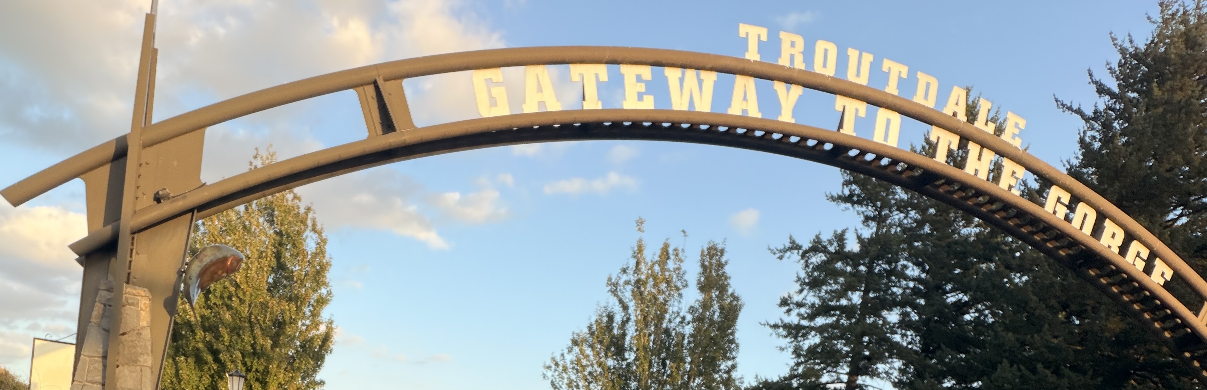 Archway reading "Gateway to the Gorge" against blue sky with trees nearby.