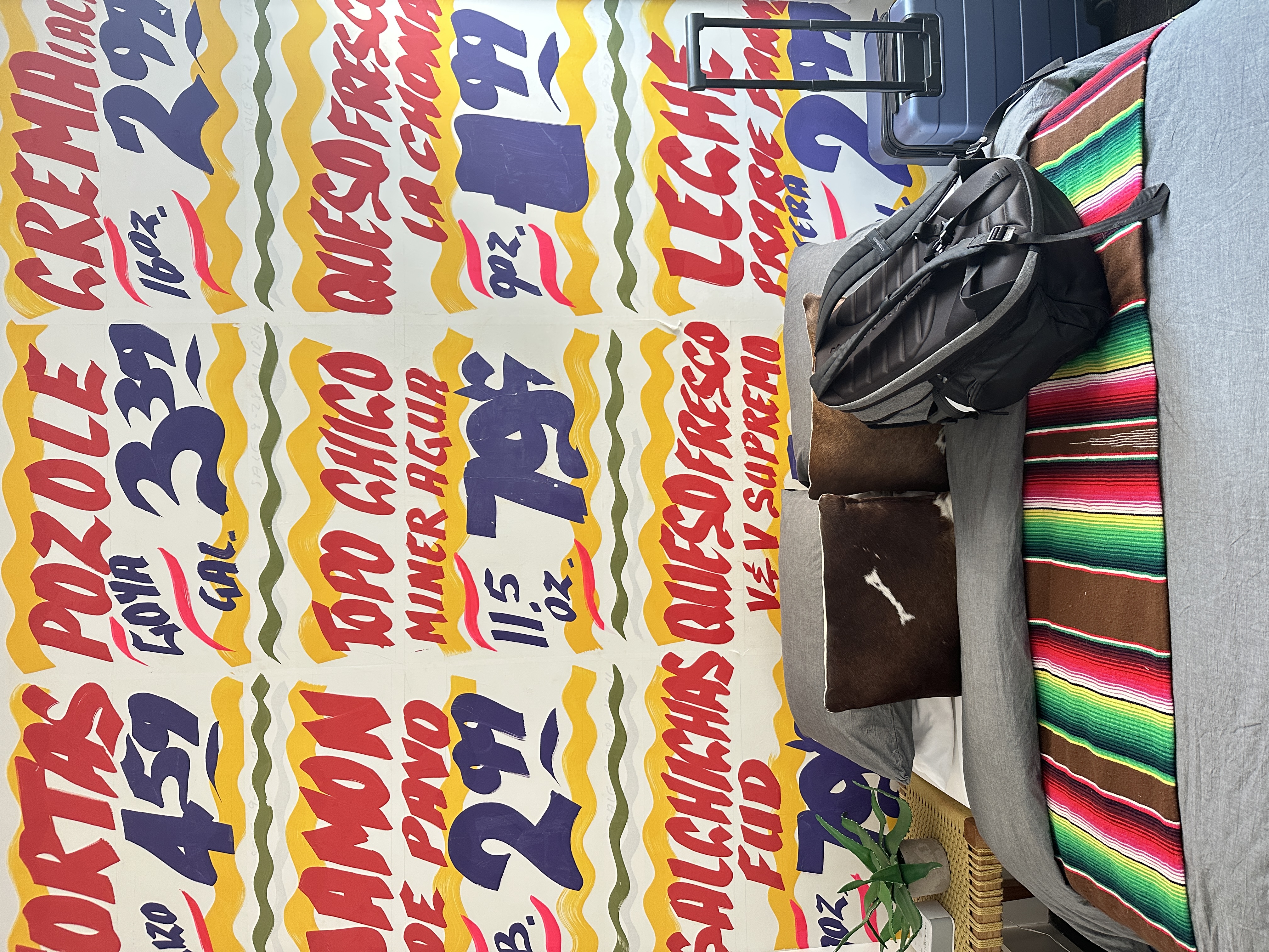 Colorful wall with bold text and a bench with a backpack and striped blanket.