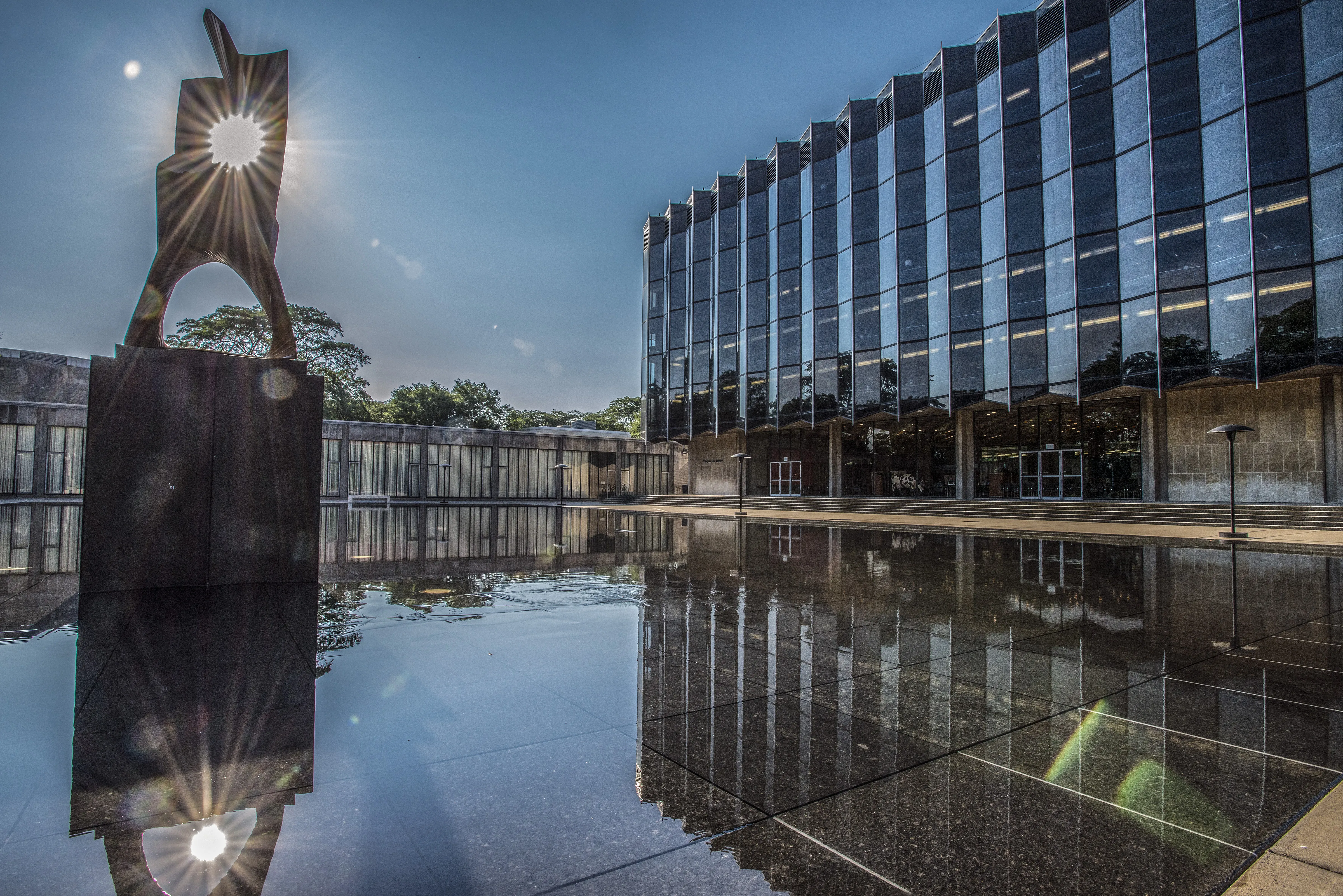 Reflective building and sculpture under a clear blue sky.