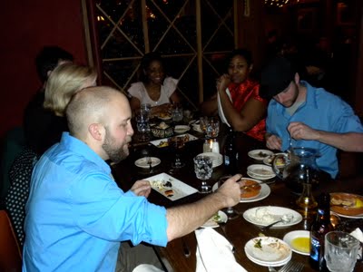 Two people dressed in blue button down shirts eat at a bar.