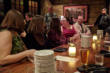 Several people socialize at a bar indoors.