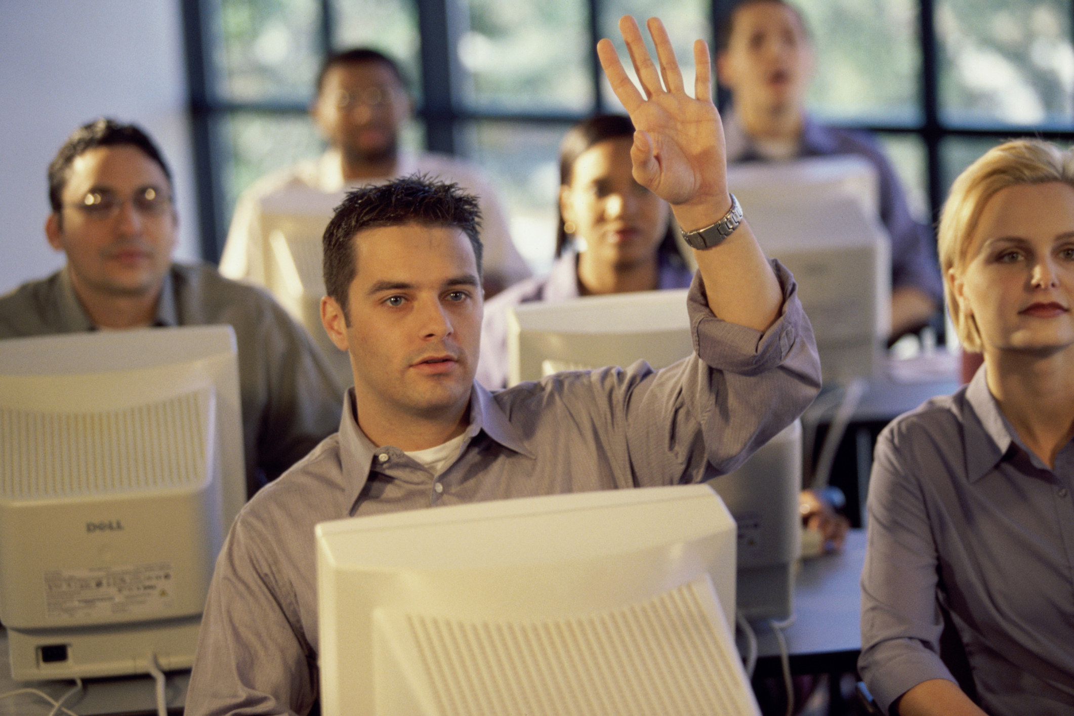 Several people in button down shirts sitting behind old computers