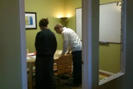 Two people in an office stand over a table while working together.