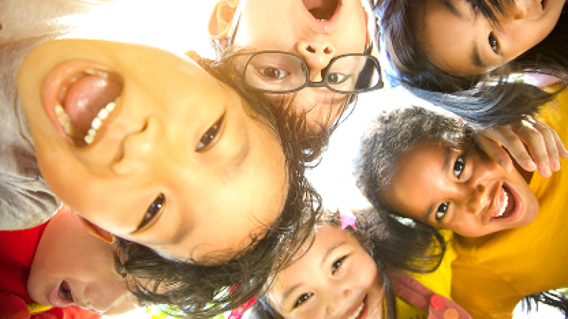 Smiling children in a circle, looking down at the camera.