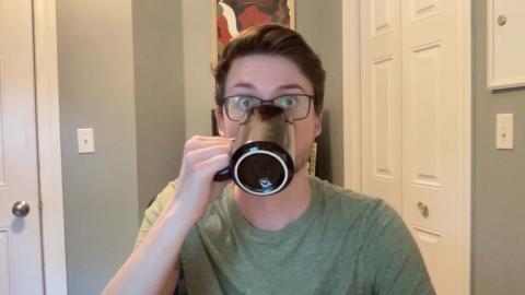 Joe Ruel is a light skinned male with brown hair, light brown facial hair, glasses, wearing a light green shirt, and drinking from a coffee cup.