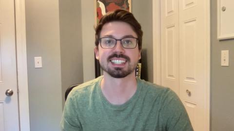 Joe Ruel is a light skinned male with brown hair, light brown facial hair, glasses, and wearing a light green shirt.