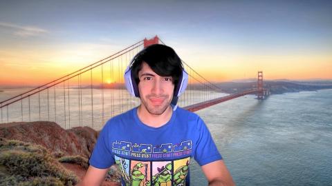 Justin Redfearn a light skinned male with black hair, headphones and a blue shirt with ninja turtles in front of a zoom background of the Golden Gate Bridge