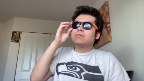 Alexander Dinh a light skinned male with black hair wearing a Seattle Seahawks shirt, putting on sunglasses