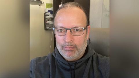 Cesar Perez a light skinned male with glasses, salt and pepper facial hair, wearing a grey sweatshirt