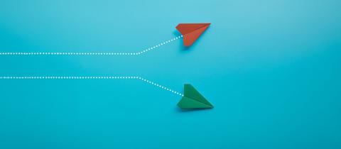 Red and green paper planes on blue background