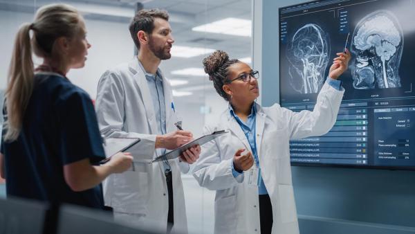 Three medical professionals looking at an MRI of a brain