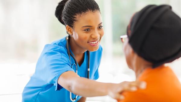African medical nurse comforting senior patient